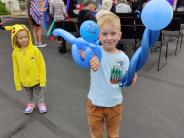 boy holds balloon creations in the foreground. In the back a girl in a Pikachu costume