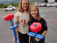 Two girls holding flower shaped balloons