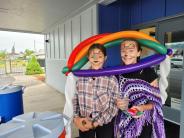 Two girls with face paint standing under an enormous balloon hat